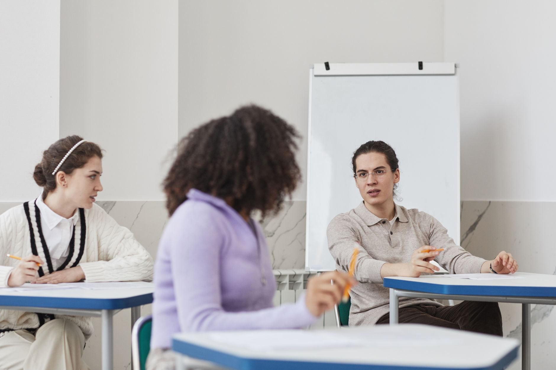 Three students engaged in a group discussion in a well-lit, modern classroom