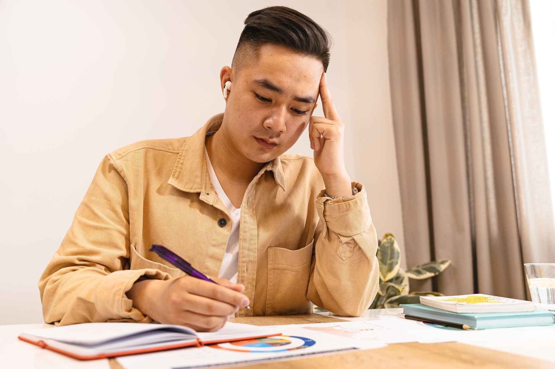 Young adult deeply focused on studying, writing notes at a desk